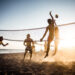 Large group of friends playing volleyball on the beach.