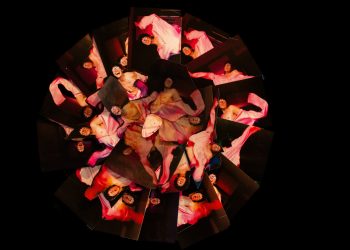 Composição circular com múltiplas imagens de pessoa envolta em tecido rosa sobre fundo preto, obra de Feio Franq
