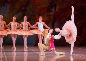 Cena de balé com bailarinos em figurinos clássicos durante apresentação de A Bela Adormecida.