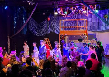 Crianças em apresentação no palco do Espaço Cultural Mapati, diante de familiares na plateia.