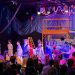 Crianças em apresentação no palco do Espaço Cultural Mapati, diante de familiares na plateia.