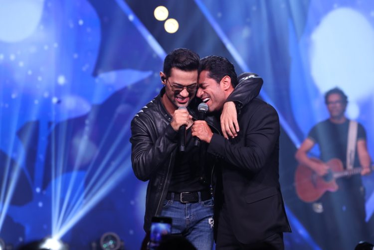 Edy Britto e Samuel cantando juntos no palco durante gravação de DVD