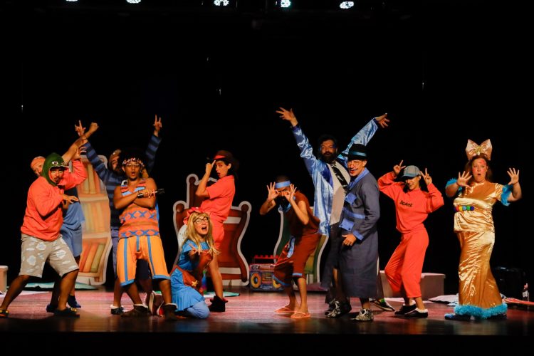 Elenco do espetáculo infantil Os Dedos da Mão do João em cena, com figurinos coloridos