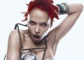FKA twigs com cabelos vermelhos, maquiagem escura e figurino de peças metálicas em foto de divulgação.