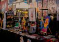 Estande da Feira MOTIM com livros, ilustrações, brinquedos artísticos e obras de arte impressa