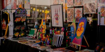 Estande da Feira MOTIM com livros, ilustrações, brinquedos artísticos e obras de arte impressa