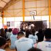 Estudantes apresentam uma cena diante da comunidade escolar, em uma quadra coberta, no projeto de leitura dramatizada no DF.