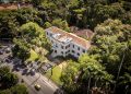 Vista aérea do prédio do Museu do Jardim Botânico, cercado por árvores no Rio de Janeiro.