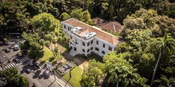 Vista aérea do prédio do Museu do Jardim Botânico, cercado por árvores no Rio de Janeiro.