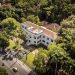 Vista aérea do prédio do Museu do Jardim Botânico, cercado por árvores no Rio de Janeiro.