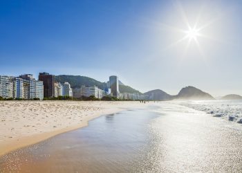 Vista panorâmica da Praia de Copacabana, com mar, faixa de areia e edifícios da orla do Rio de Janeiro