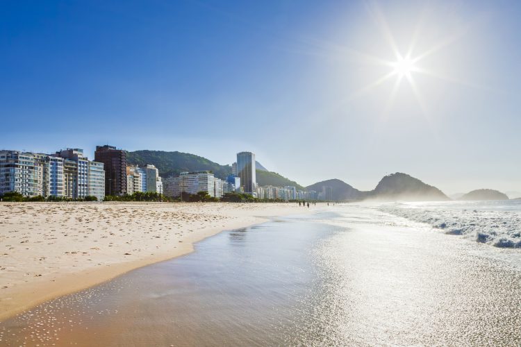 Vista panorâmica da Praia de Copacabana, com mar, faixa de areia e edifícios da orla do Rio de Janeiro