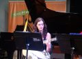 Violonista toca durante a Revirada Musical da EMESP Tom Jobim, com piano e estante de partituras no palco.