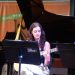Violonista toca durante a Revirada Musical da EMESP Tom Jobim, com piano e estante de partituras no palco.