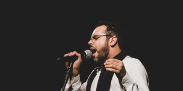 Vocalista da banda Sereníssima canta ao microfone em foto de divulgação