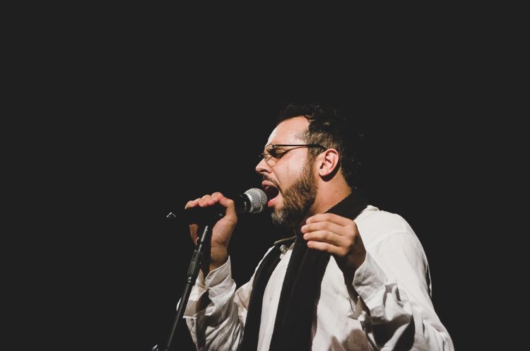 Vocalista da banda Sereníssima canta ao microfone em foto de divulgação