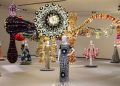 Vista oficial de VENUS no MAAT: manequins com vestidos de Valentino diante da instalação têxtil monumental de Joana Vasconcelos.