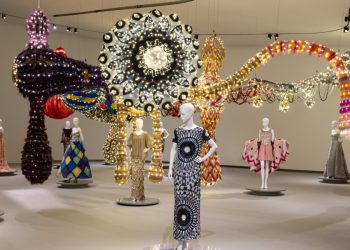 Vista oficial de VENUS no MAAT: manequins com vestidos de Valentino diante da instalação têxtil monumental de Joana Vasconcelos.