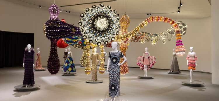 Vista oficial de VENUS no MAAT: manequins com vestidos de Valentino diante da instalação têxtil monumental de Joana Vasconcelos.