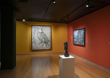 Vista da exposição de Vik Muniz no CCBB Rio de Janeiro, com fotografias em paredes amarelas e vermelhas e escultura sobre pedestal.